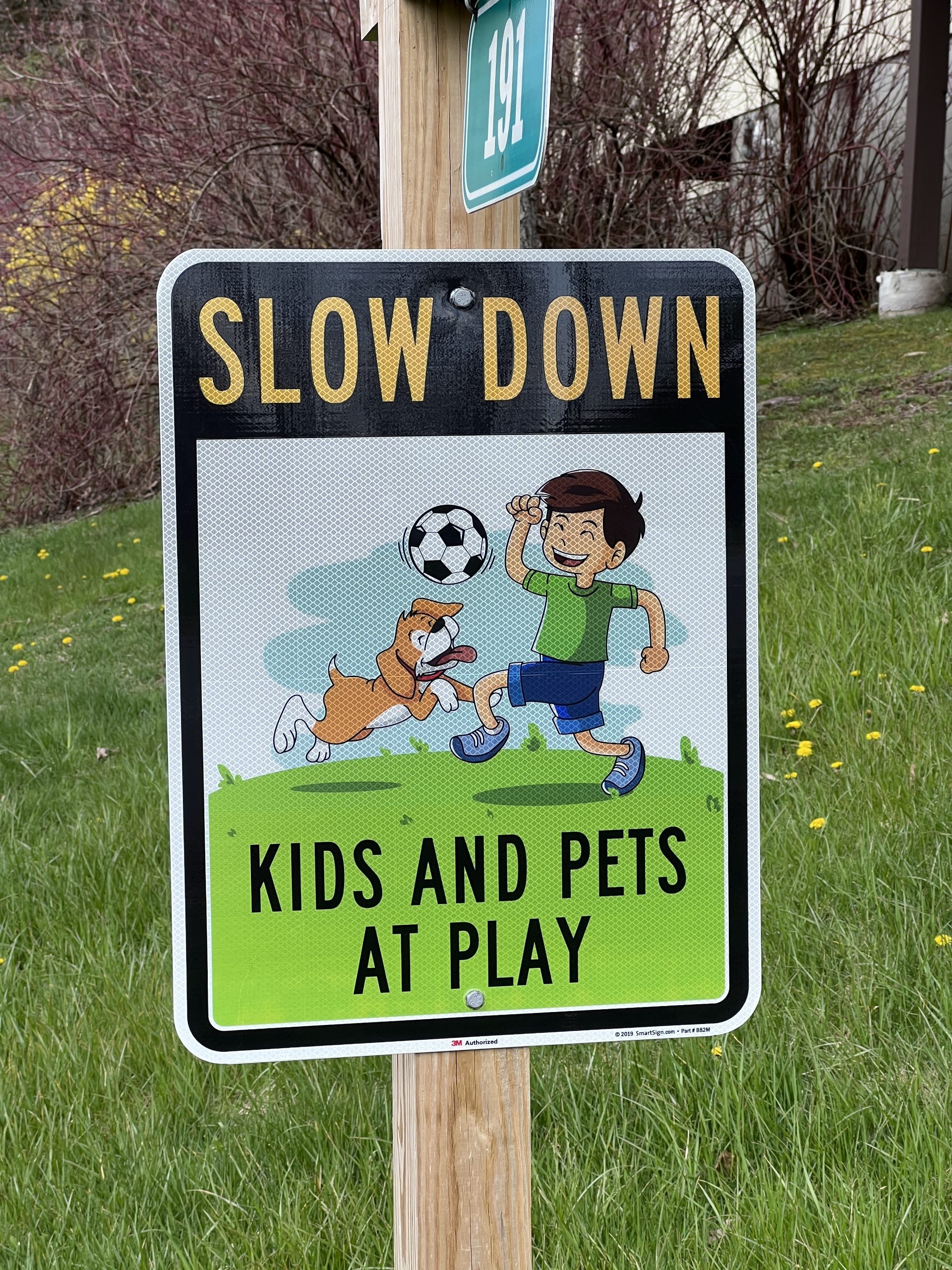 Road sign on a wooden post: Slow Down - Kids and Pets at play